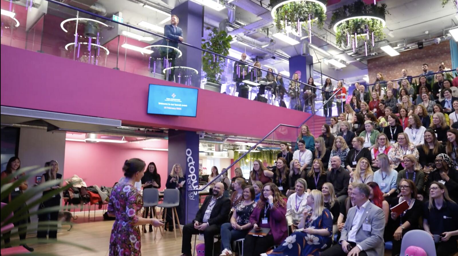 Guests at an indoor product launch below a lit stage