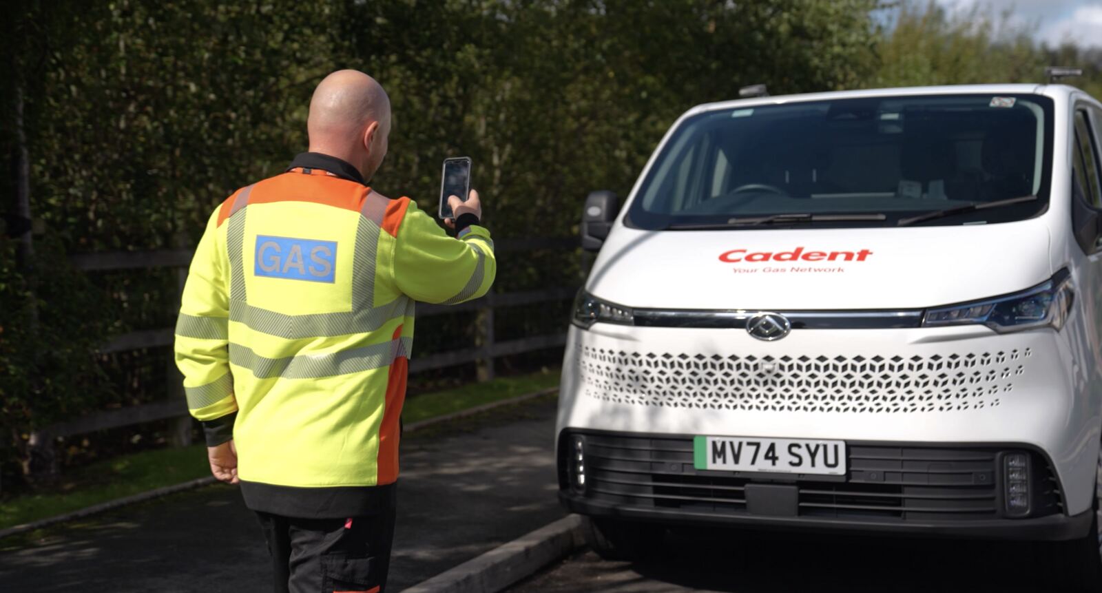 Engineer photographing a white gas van on a phone
